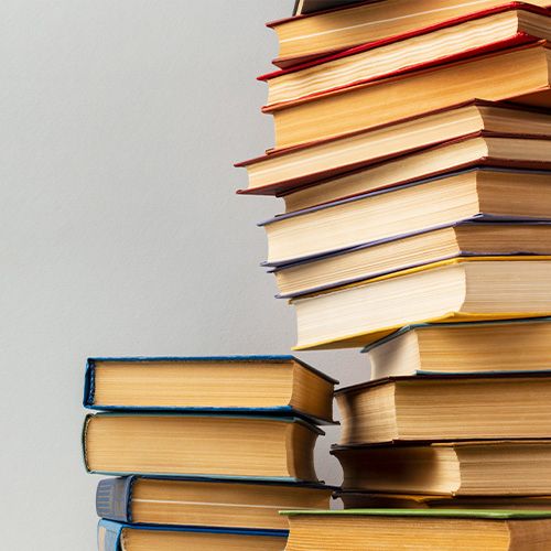 Una imagen que muestra varias pilas de libros de diferentes tamaños y colores sobre un fondo liso y claro.